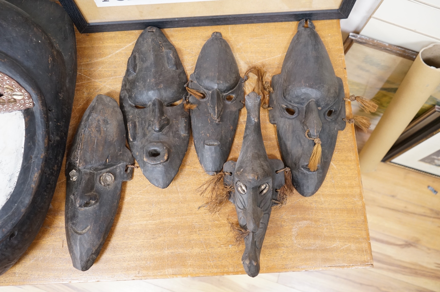 A Papua New Guinea Sepik River large carved wooden mask, painted in black and white and applied with pig tusks and teeth, together with five small plain masks, largest 82cm high